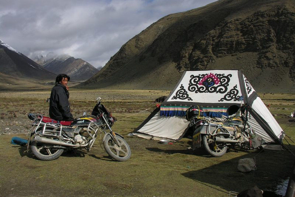 In Tibet wurden die Pferde der Nomaden heute weitgehend durch Motorräder ersetzt. Im Hintergrund das Zelt von Raupenpilzsammlern