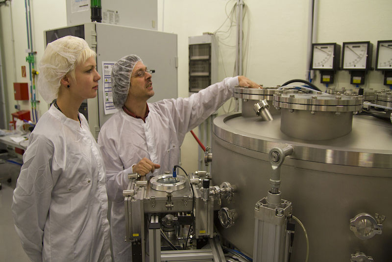 Kristin Suckau und Dr. Hartmut Leipner an der Vakuumbeschichtungsmaschine im Reinraum.