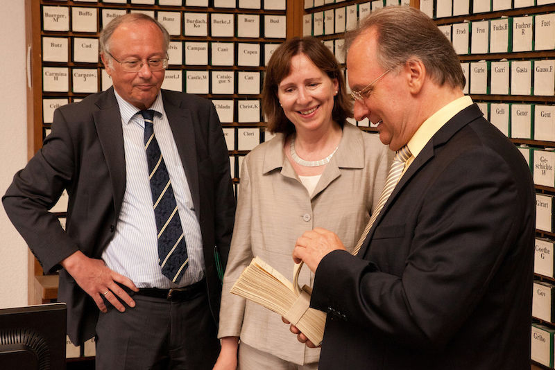 Rektor Udo Sträter, Bibliotheksleiterin Dorothea Sommer mit Reiner Haseloff (v.l.) beim Entdecken des  historischen Strumpfbandkatalogs.