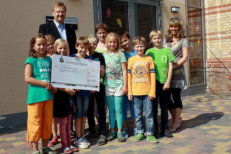 Prof. Dr. Stephan Feller übergibt einen Scheck über 500 Euro an die Grundschule Kröllwitz.