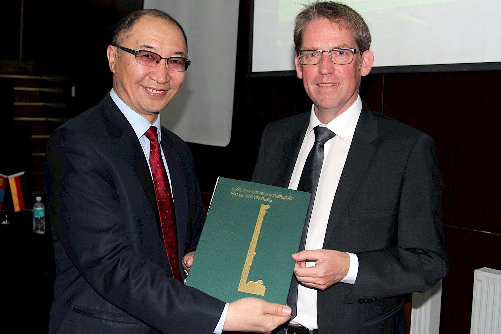 Prorektor Michael Bron überreicht NUM-Rektor Regsuren Bat-Erdene eine Reproduktion einer historischen Grußadresse der Uni Halle an die NUM.