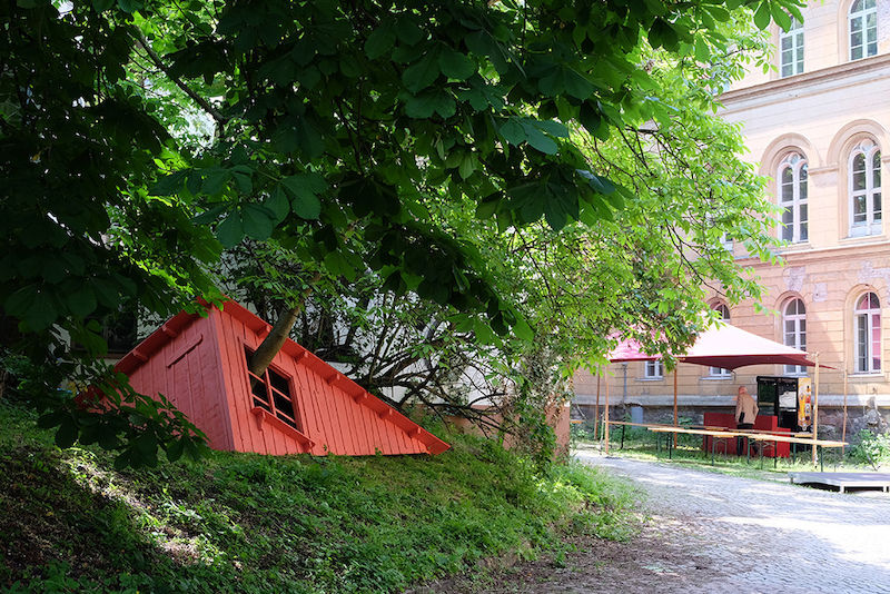 Eine rote Hausecke lädt zur Besichtigung ein.
