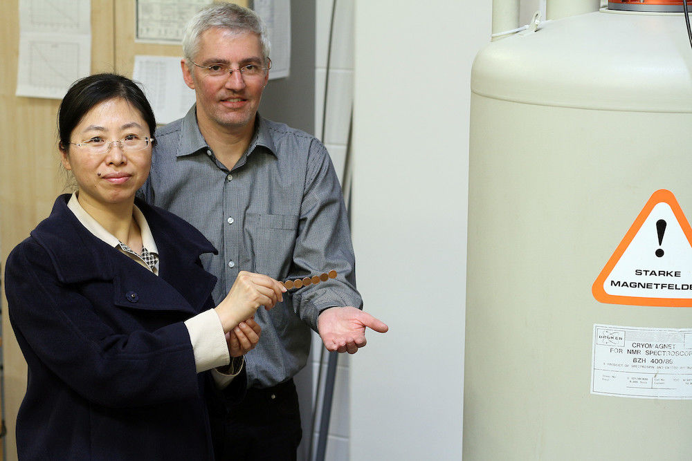 Anziehende Forschung: Der hallesche Biophysiker Prof. Dr. Jochen Balbach zeigt seiner chinesischen Kollegin Prof. Dr. Zhao-Yan Sun ein NMR-Spektroskop. Die Magnetfelder, die im Inneren der Maschine erzeugt werden, sind so stark, dass sie trotz Abschirmhülle eisenhaltige Münzen anziehen können.