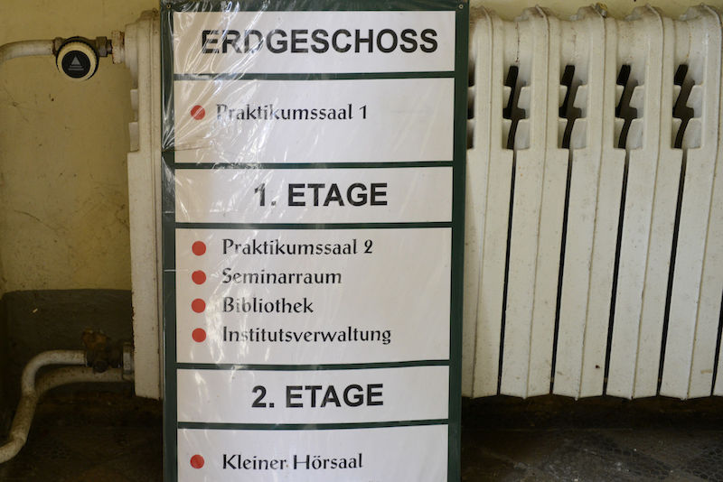 Das alte Schild weist noch den Weg zu Sälen, Bibliothek oder Verwaltung.