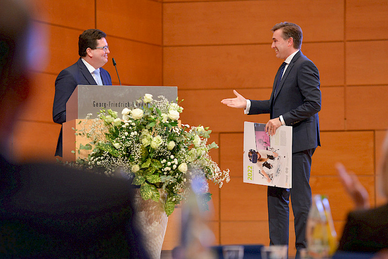 Staatssekretär Thomas Wünsch (rechts) erhielt von Rektor Christian Tietje den ersten Deutschlandstipendien-Kalender für 2022.