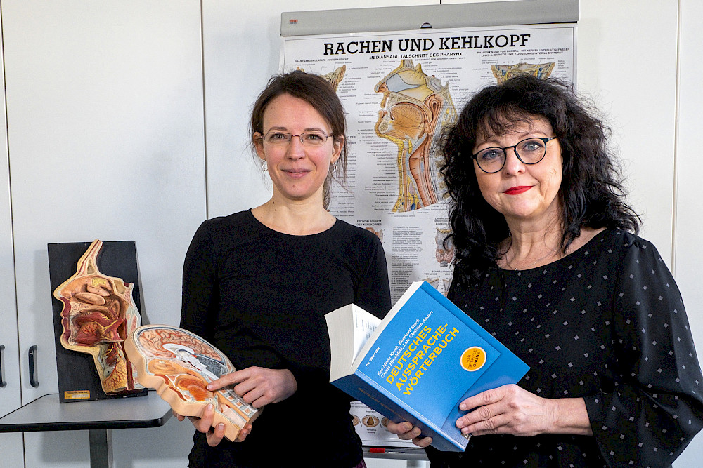 Alexandra Ebel (links) und Susanne Voigt-Zimmermann mit den Objekten, die für die Digitalisierung genutzt werden: das gedruckte Buch und ein Schnittmodell des Kopfs.
