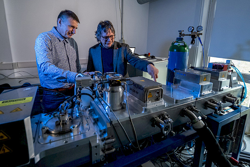 NORCSI-Geschäftsführer Udo Reichmann (links) und MLU-Forscher Hartmut Leipner stehen vor einer Hochvakuum-Beschichtungsanlage zur Herstellung von Anodenschichten