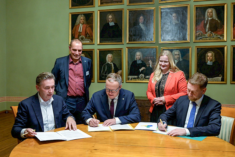 Sachsen-Anhalts Wissenschafts-Staatssekretär Thomas Wünsch, Thüringens Ministerpräsident Mario Voigt und Sachsens Ministerpräsident Michael Kretschmer unterzeichnen eine Absichtserklärung zur Förderung von iDiv über 2030 hinaus.