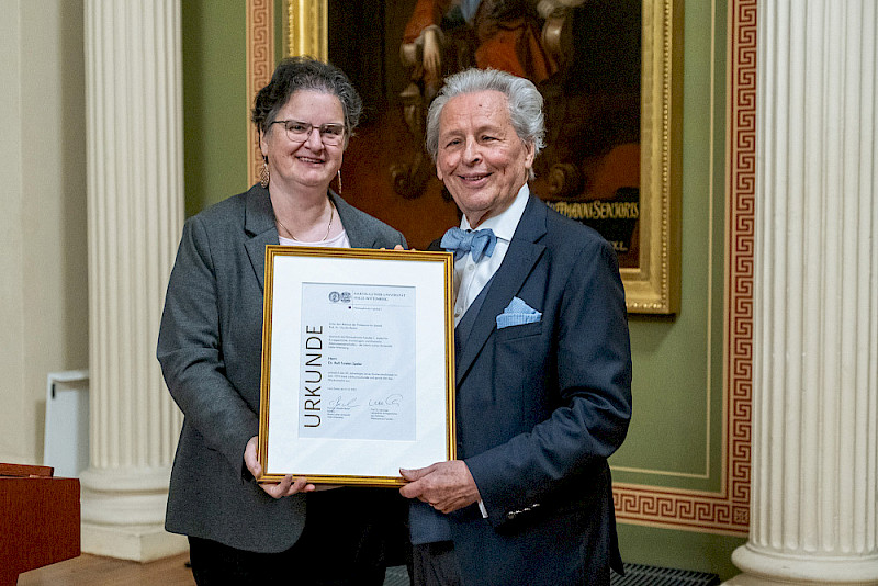 Rektorin Claudia Becker überreichte zur Mitgliederversammlung noch eine besondere Ehrung an Ralf-Torsten Speler: die Urkunde zum 50-jährigen Jubiläum seines Studienabschlusses an der MLU.