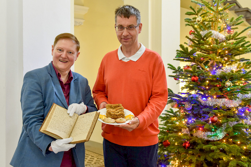 Julia Knödler und Martin Scheuplein von der ULB präsentieren das älteste Kochbuch der ULB von 1697 und drei Backwaren nach historischen Rezepten.