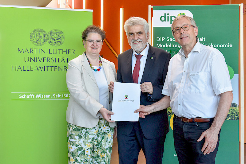 Wissensenschaftsminister Armin Willingmann (Mitte) übergibt den Förderbescheid an Rektorin Claudia Becker und Klaus Pillen